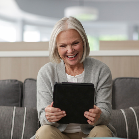 Woman smiling while reading a tablet