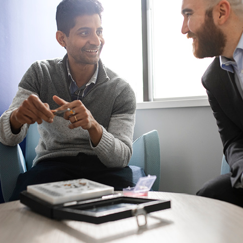 Two men looking at a hearing aid