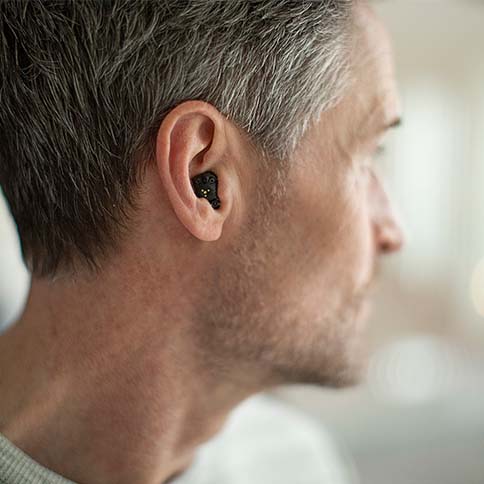 Profile of man wearing hearing aids.