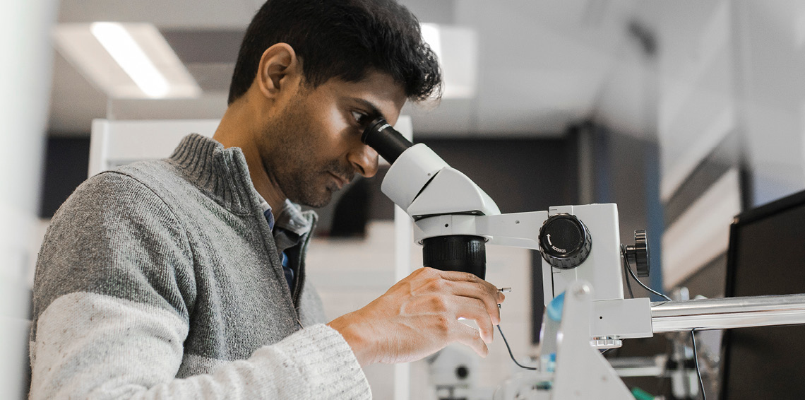 Male looking into a microscope