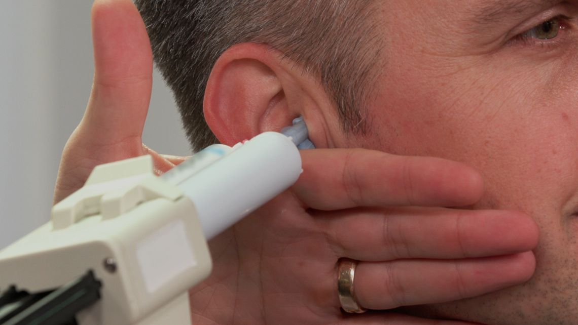 A close up on impression material being injected into a man's ear canal.
