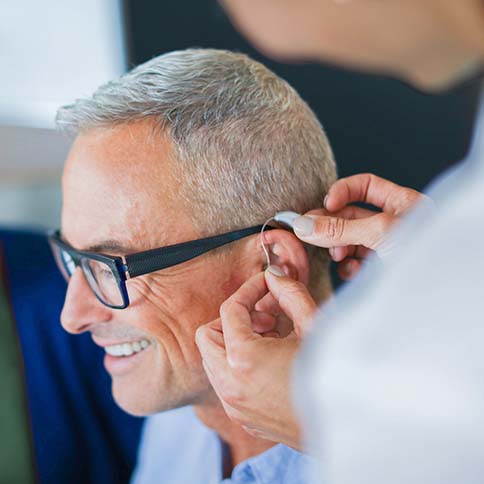 Professional fitting a hearing aid on a man.