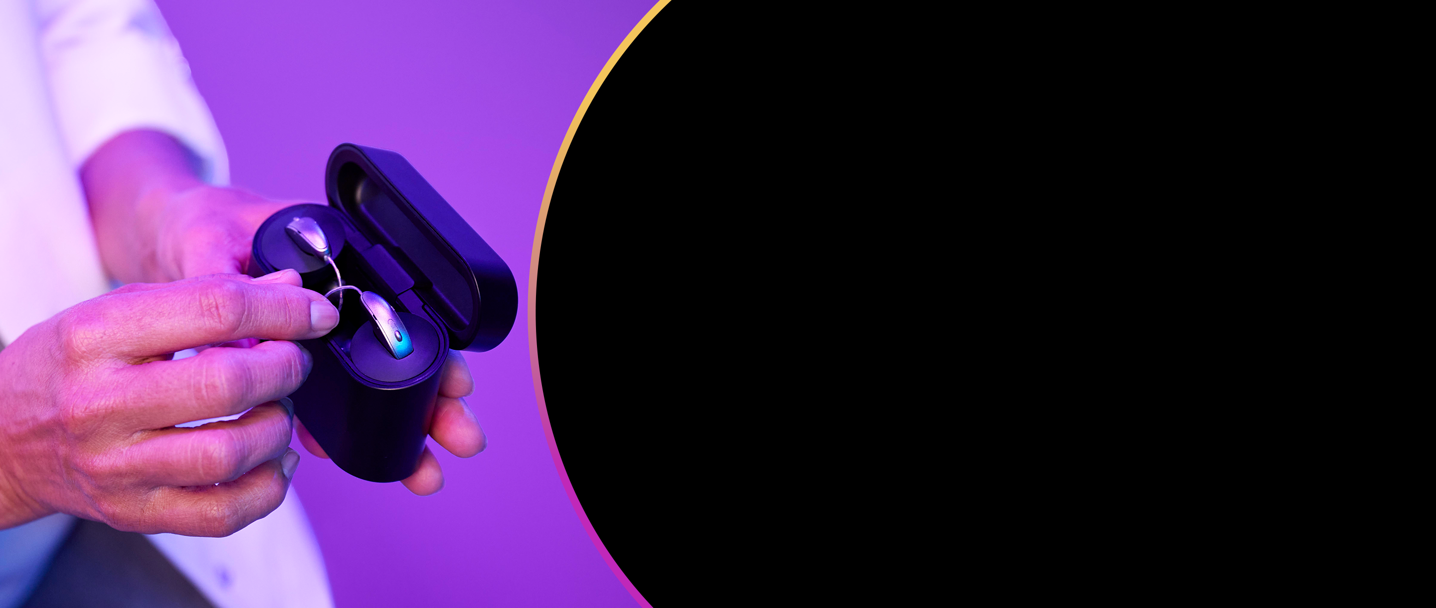 Hand holding hearing aids in a StarLink charger.