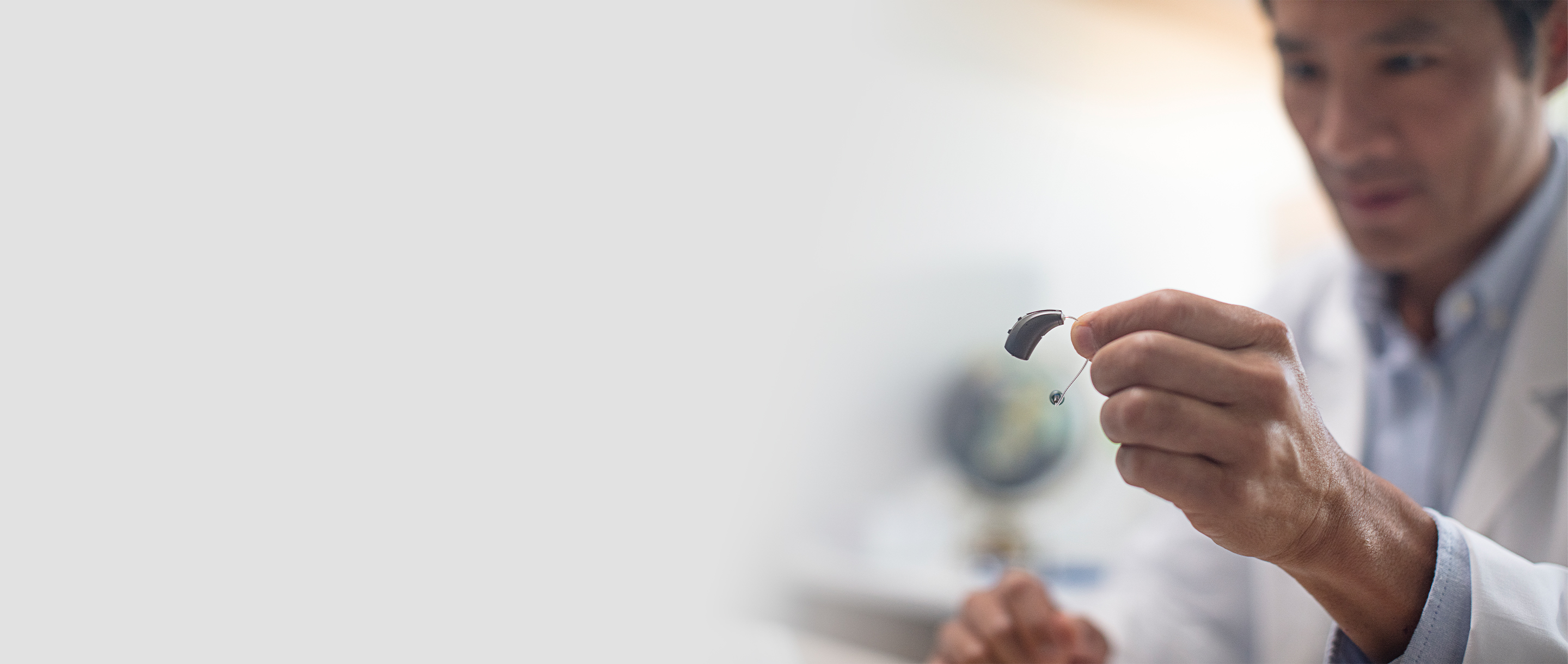 A male hearing professional holding a receiver-in-canal hearing aid