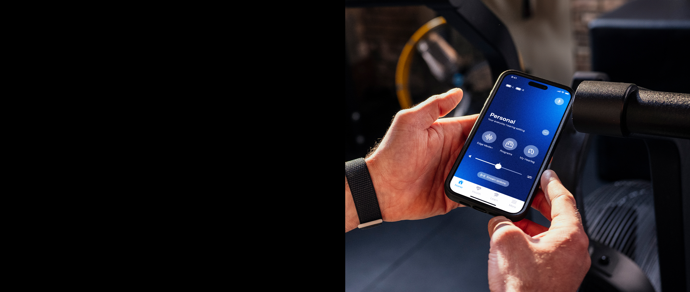 Hands holding a phone with the My Starkey app on the screen.