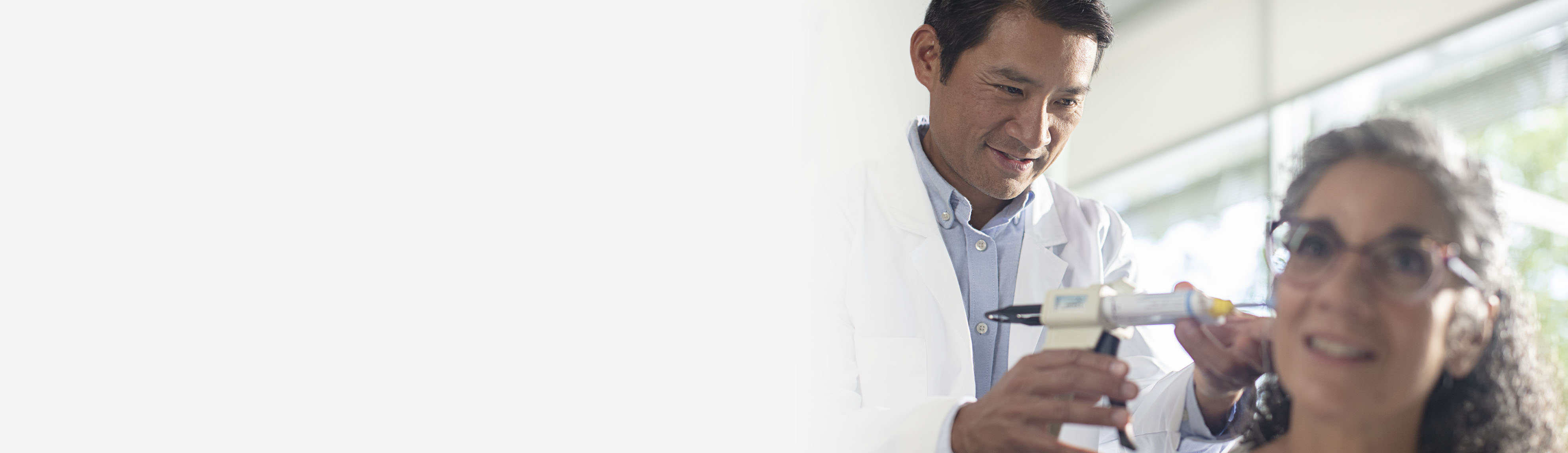 A hearing specialist injecting impression material in a woman's ear.