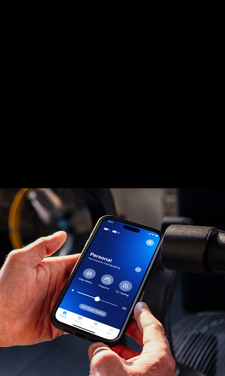 Hands holding a phone with the My Starkey app on the screen.