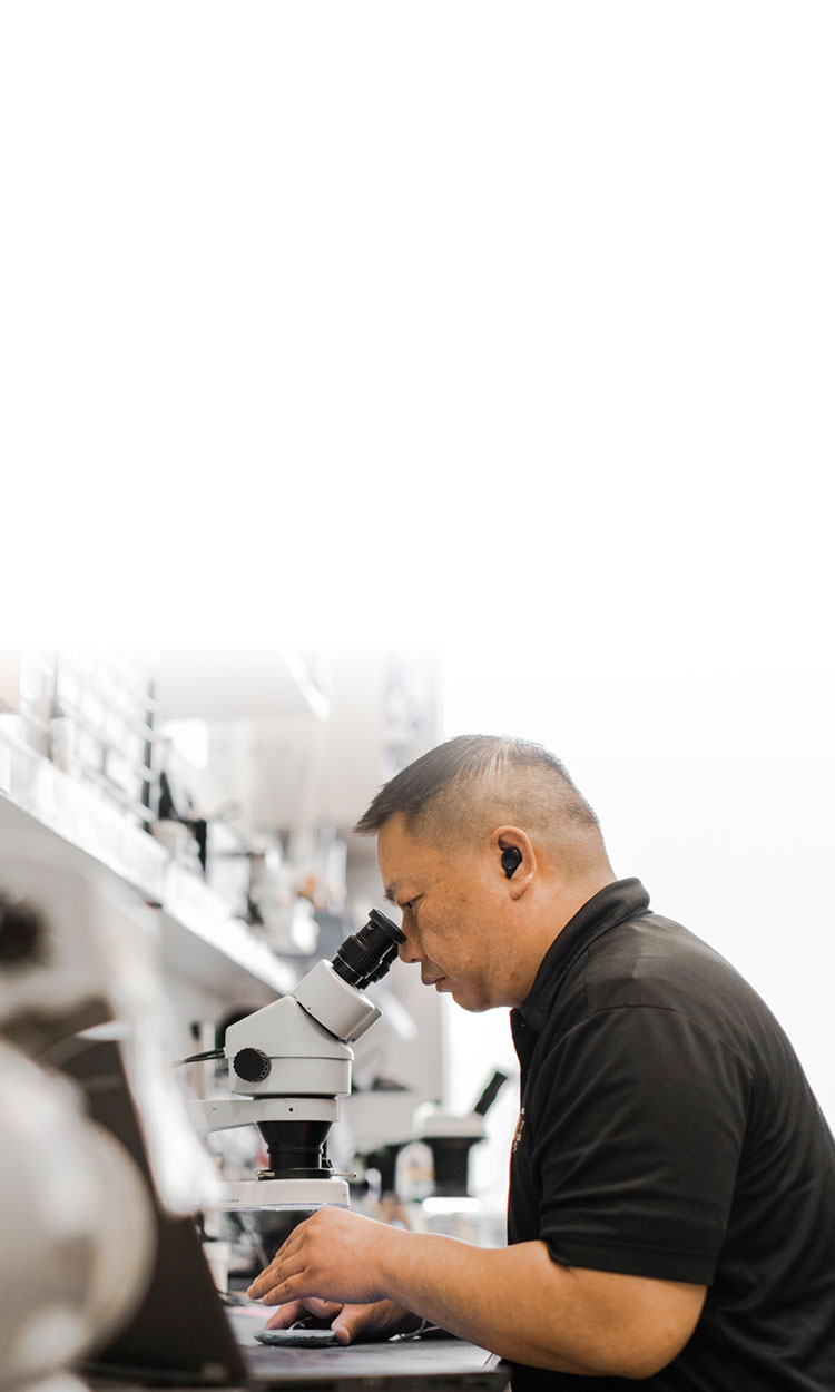 A man using a microscope to look at a circuit