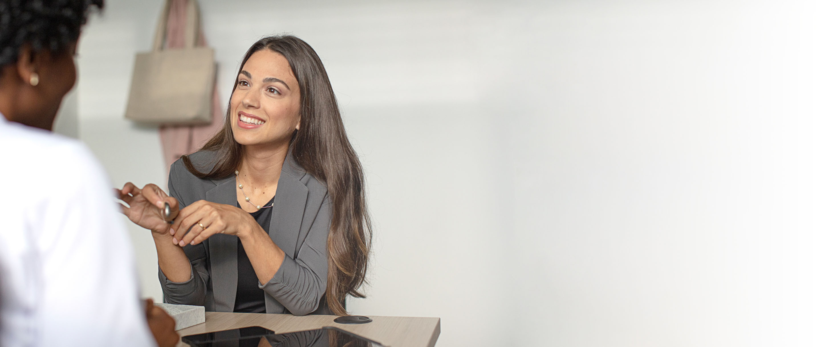 A hearing professional talking to a woman holding a hearing aid