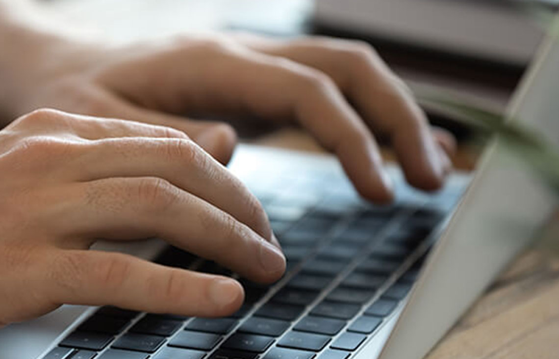 Hands typing on a laptop keyboard