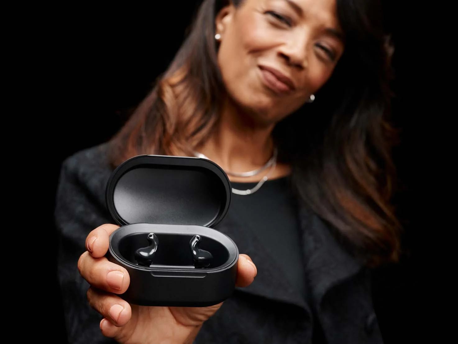 woman holding a charging case containing hearing aids