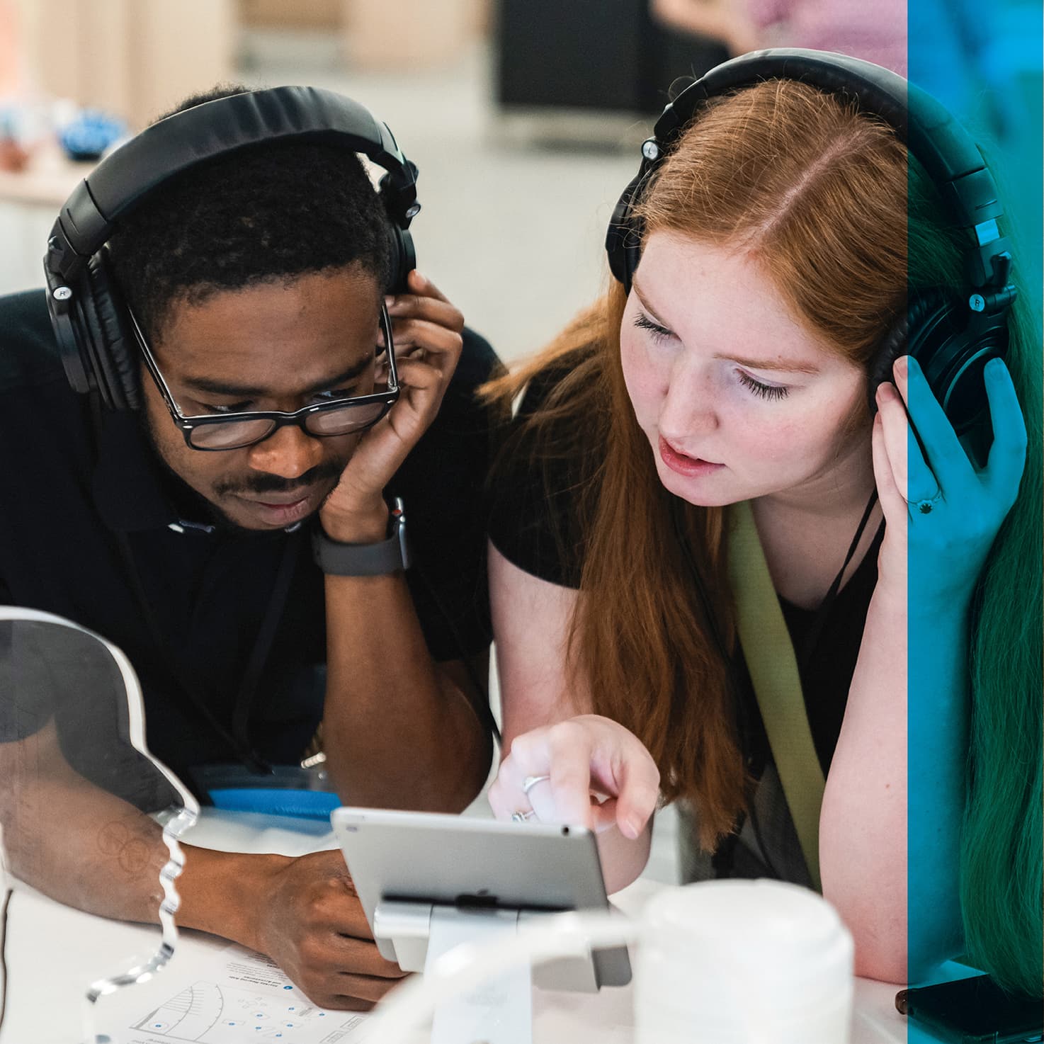 two students with headphones viewing a tablet