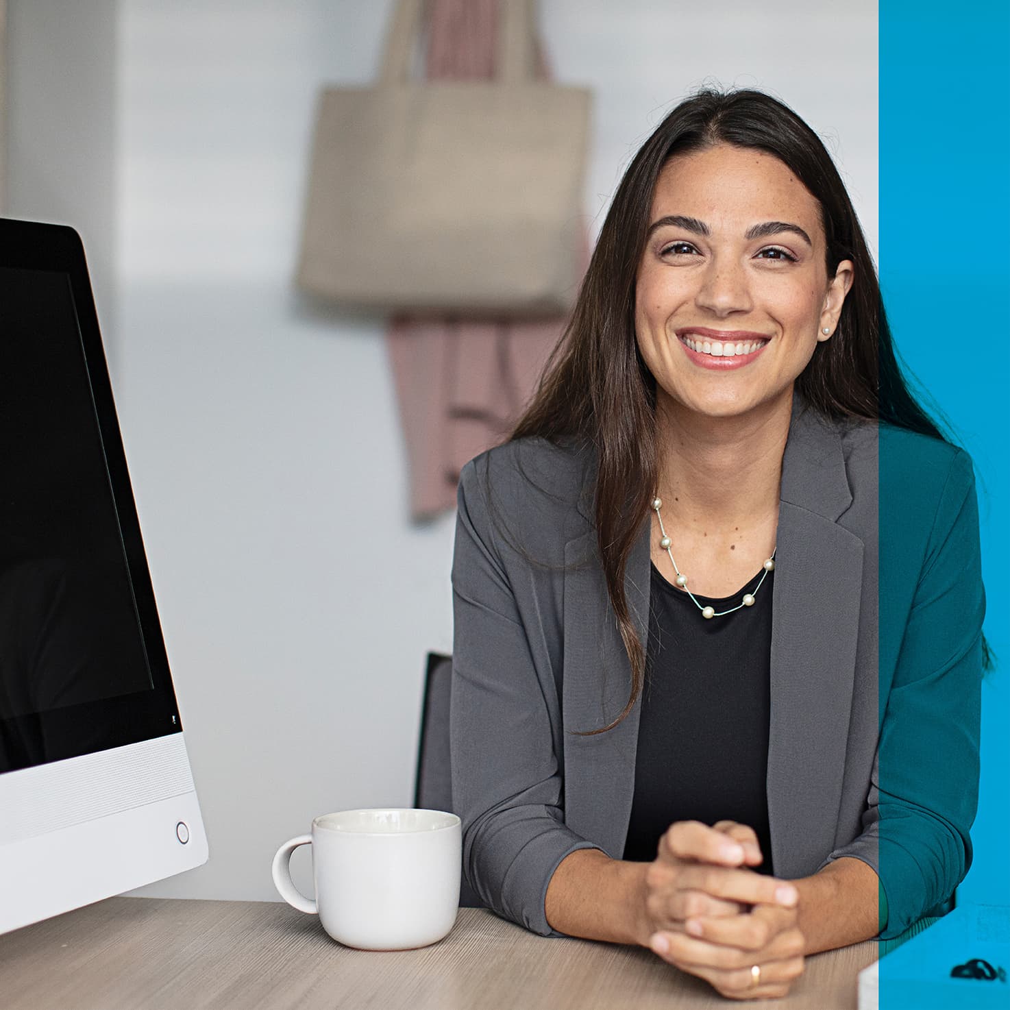 woman sitting beside a computer desk, smiling